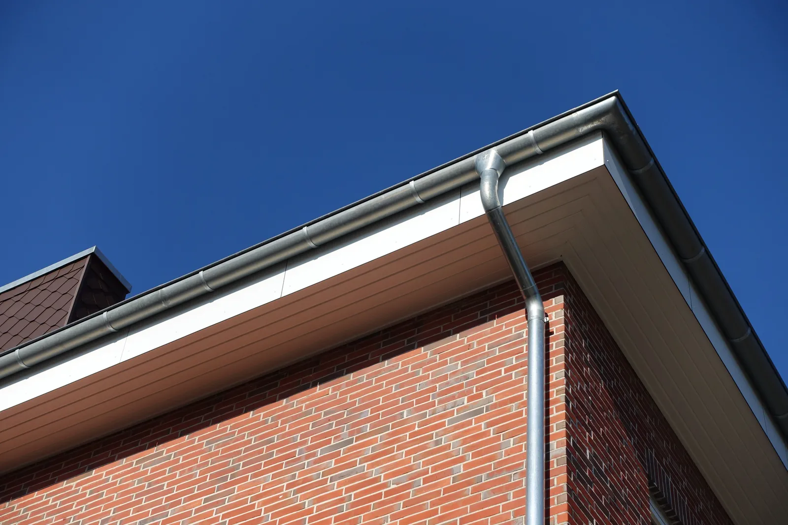 Grey guttering and brown UPVC soffit fitted along a red brick roofline in Devizes