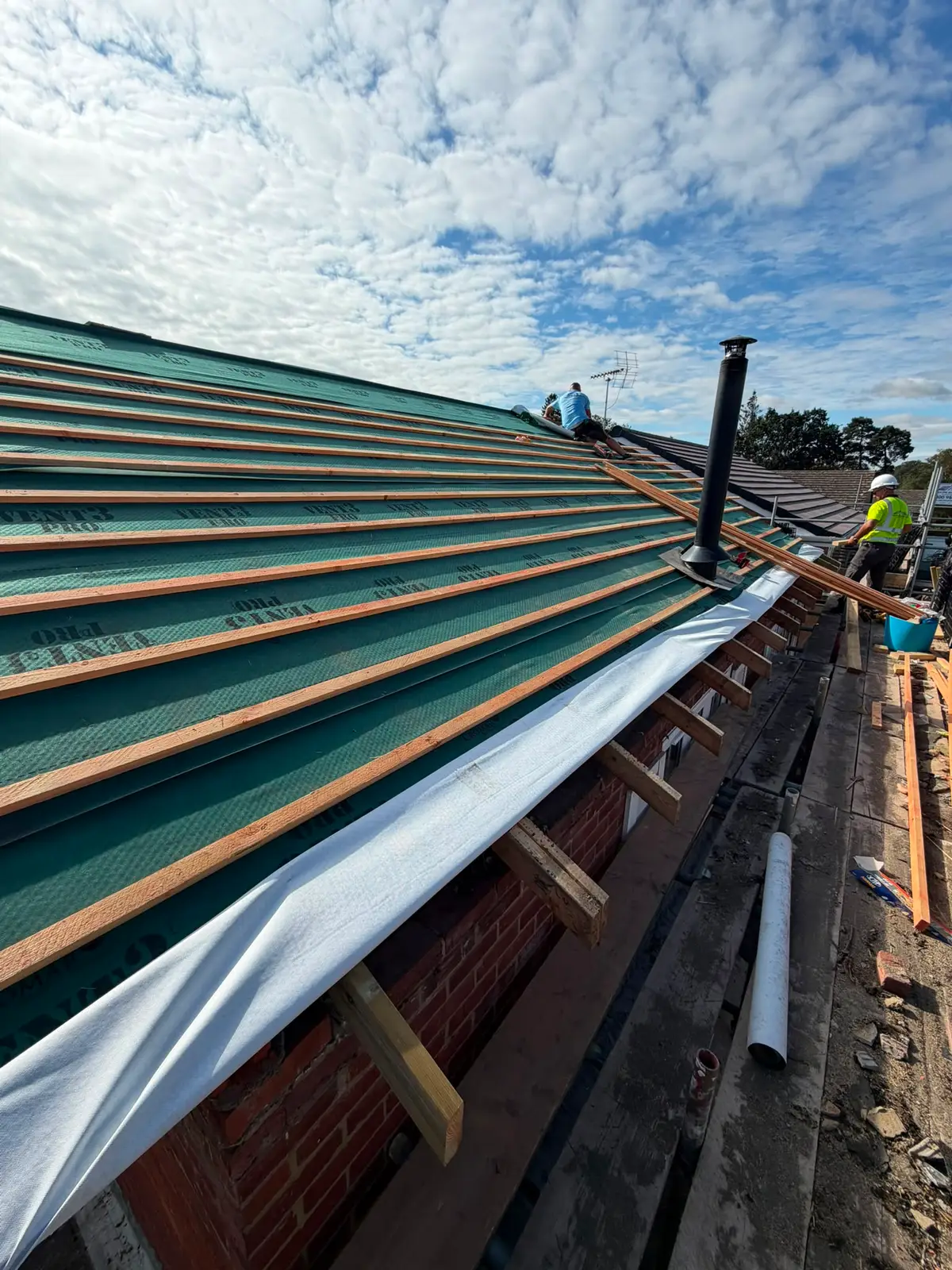 Roofers installing battens over breathable felt on a Newbury re-roof