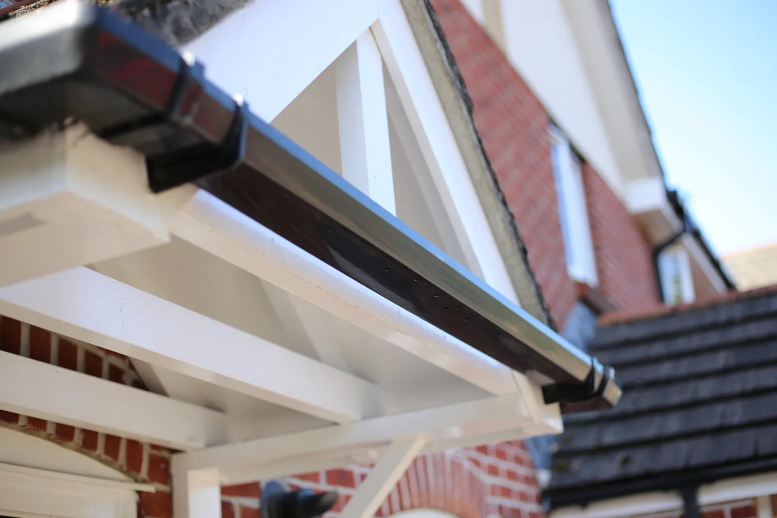Black square-profile guttering fitted along a white porch gable in Bath