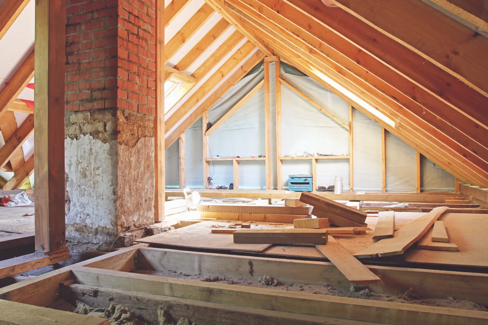 Loft conversion in progress with floor boards laid beside timber roof trusses