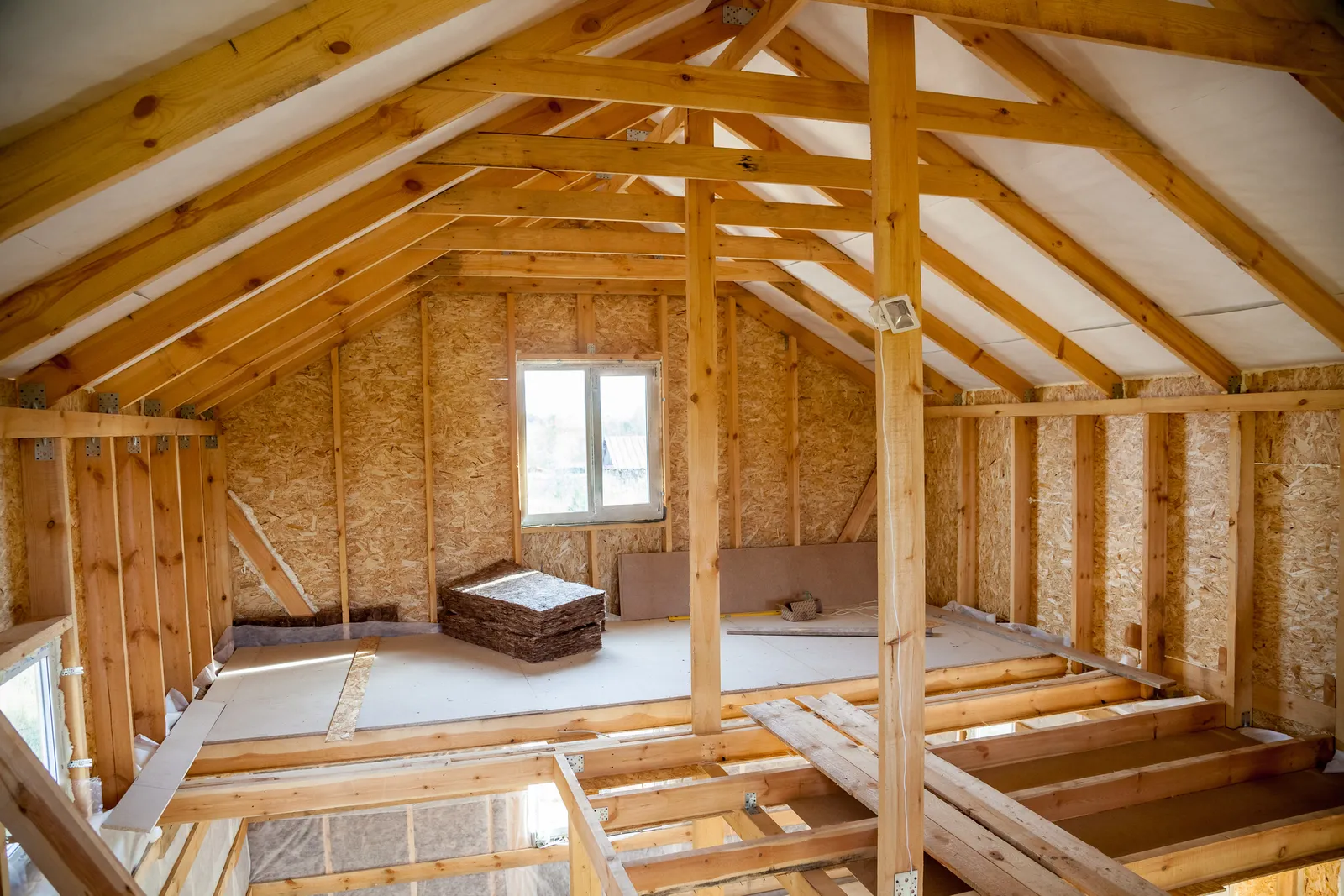 Partially boarded loft floor with timber trusses and a roof window