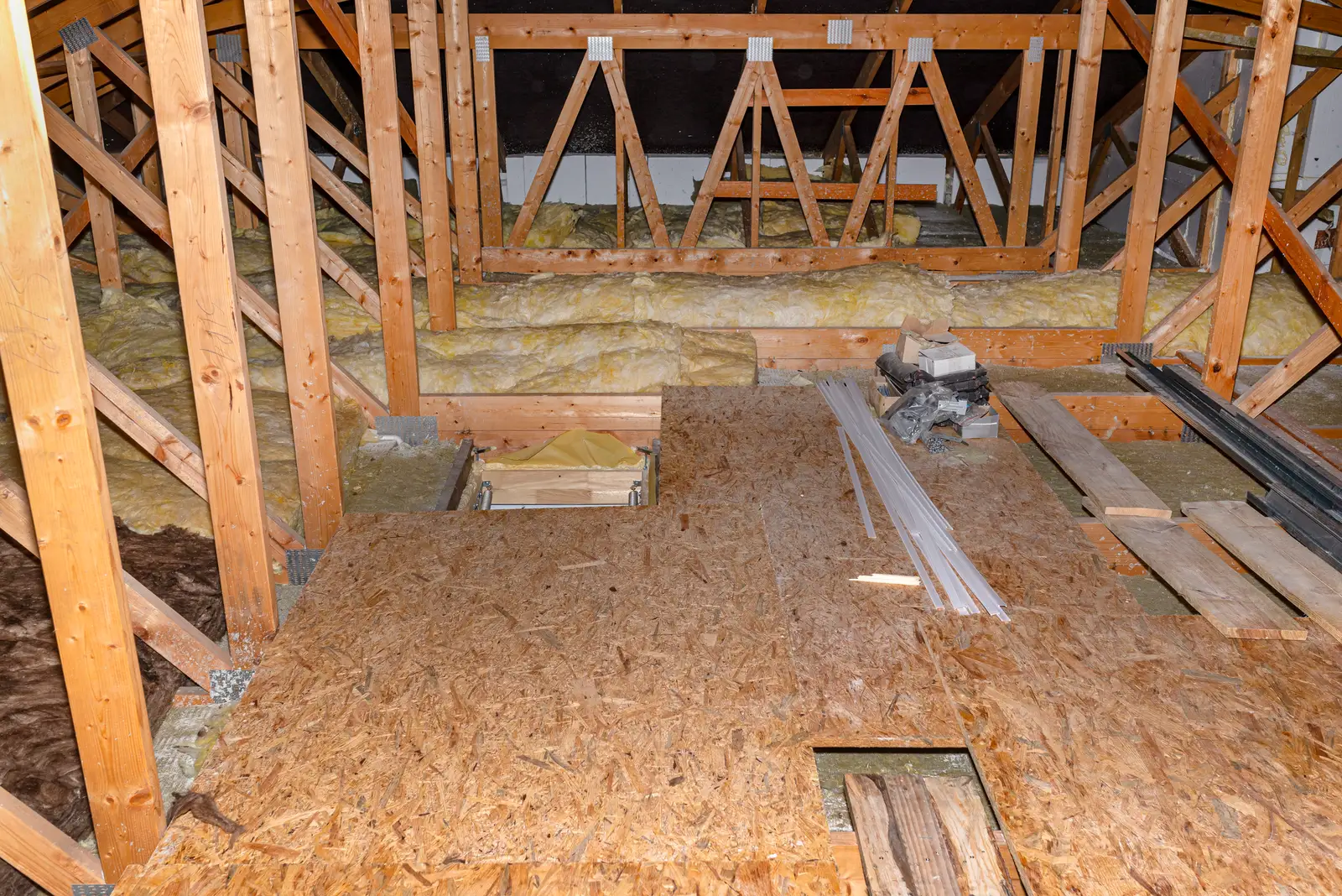 Raised loft boarding fitted over mineral wool insulation beside an insulated hatch