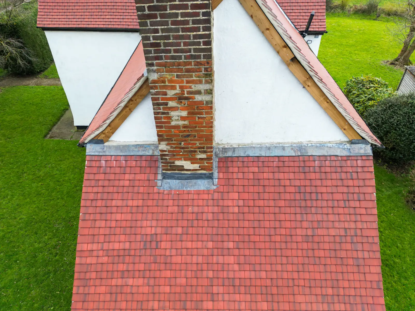 Aerial view of a red clay tile roof meeting a rendered chimney breast in Devizes